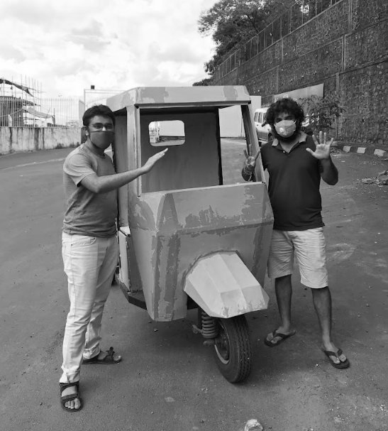 Black-and-white photo of two team members presenting the L3 prototype with its grey folded cab