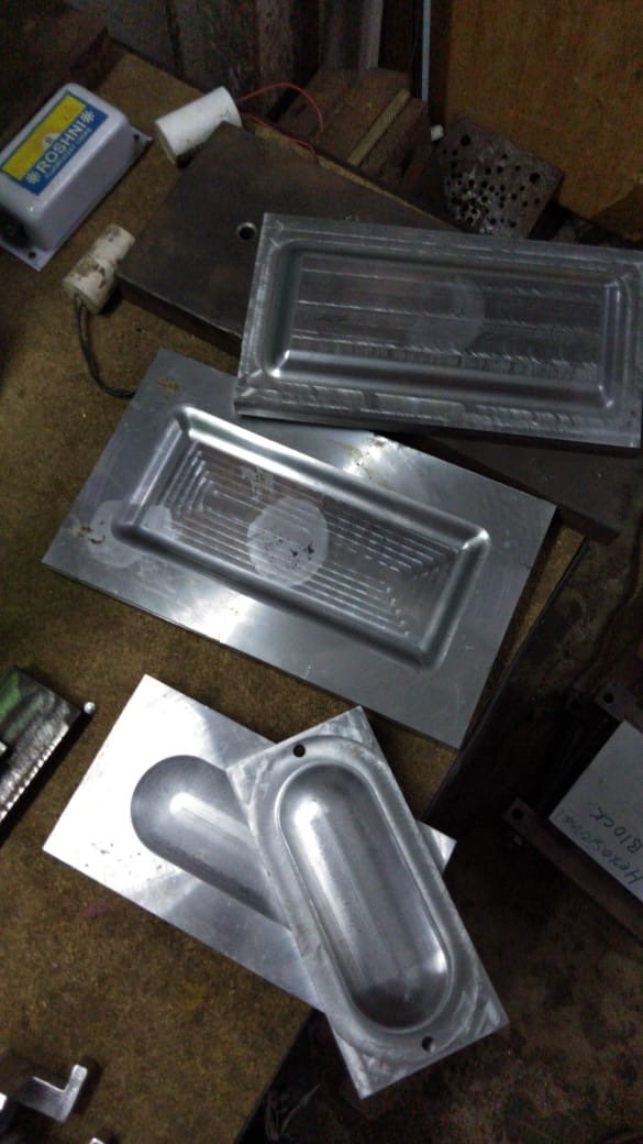 A machined draw die and formed sheet-metal part on the workshop bench