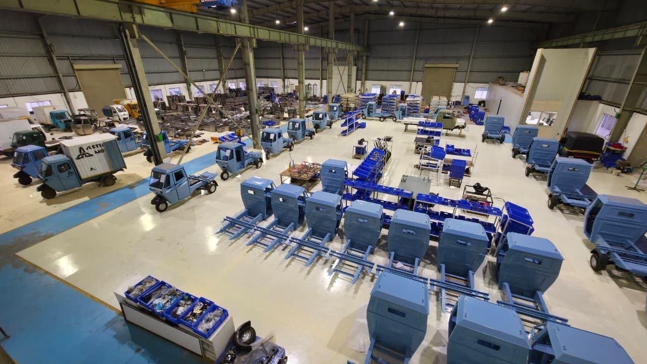 Wide view of the Astro Motors factory floor with rows of blue vehicles and cargo boxes in assembly