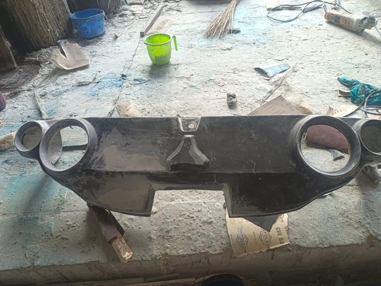 Black FRP headlight moulds laid out on the workshop floor