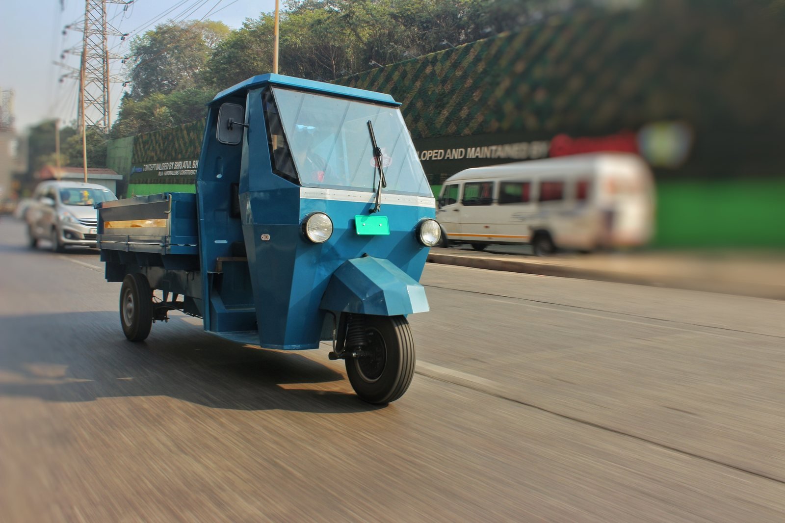 A pilot-batch Navya electric cargo three-wheeler driving on the road, in Astro Motors blue