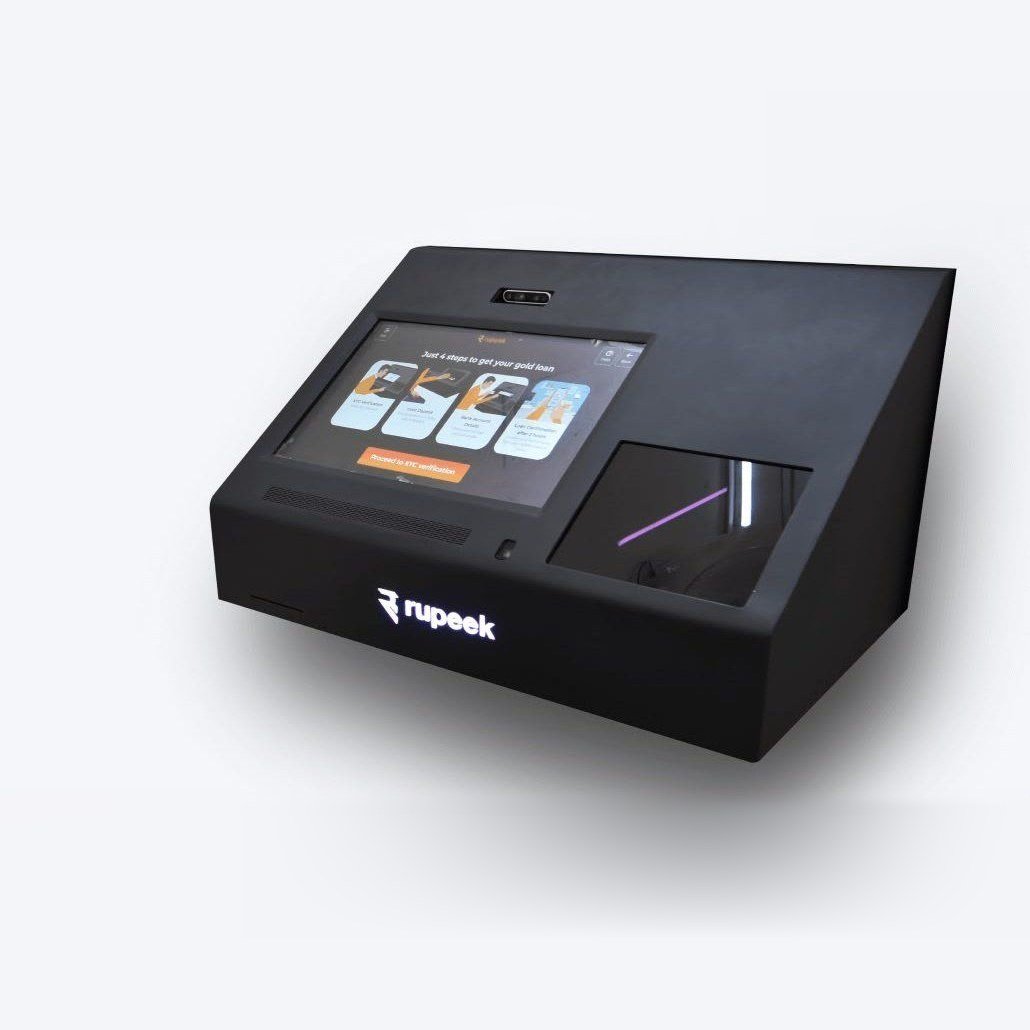 The Rupeek Gold Teller Machine — a black desk-height kiosk with an angled touchscreen and a gold tray